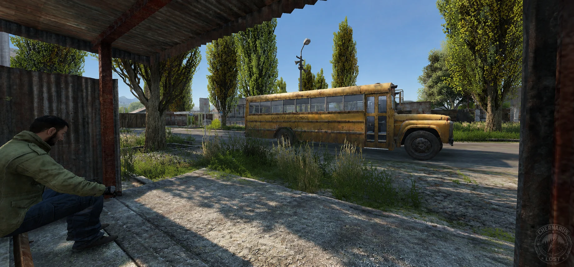A seated survivor at a roadside shelter near a yellow bus.