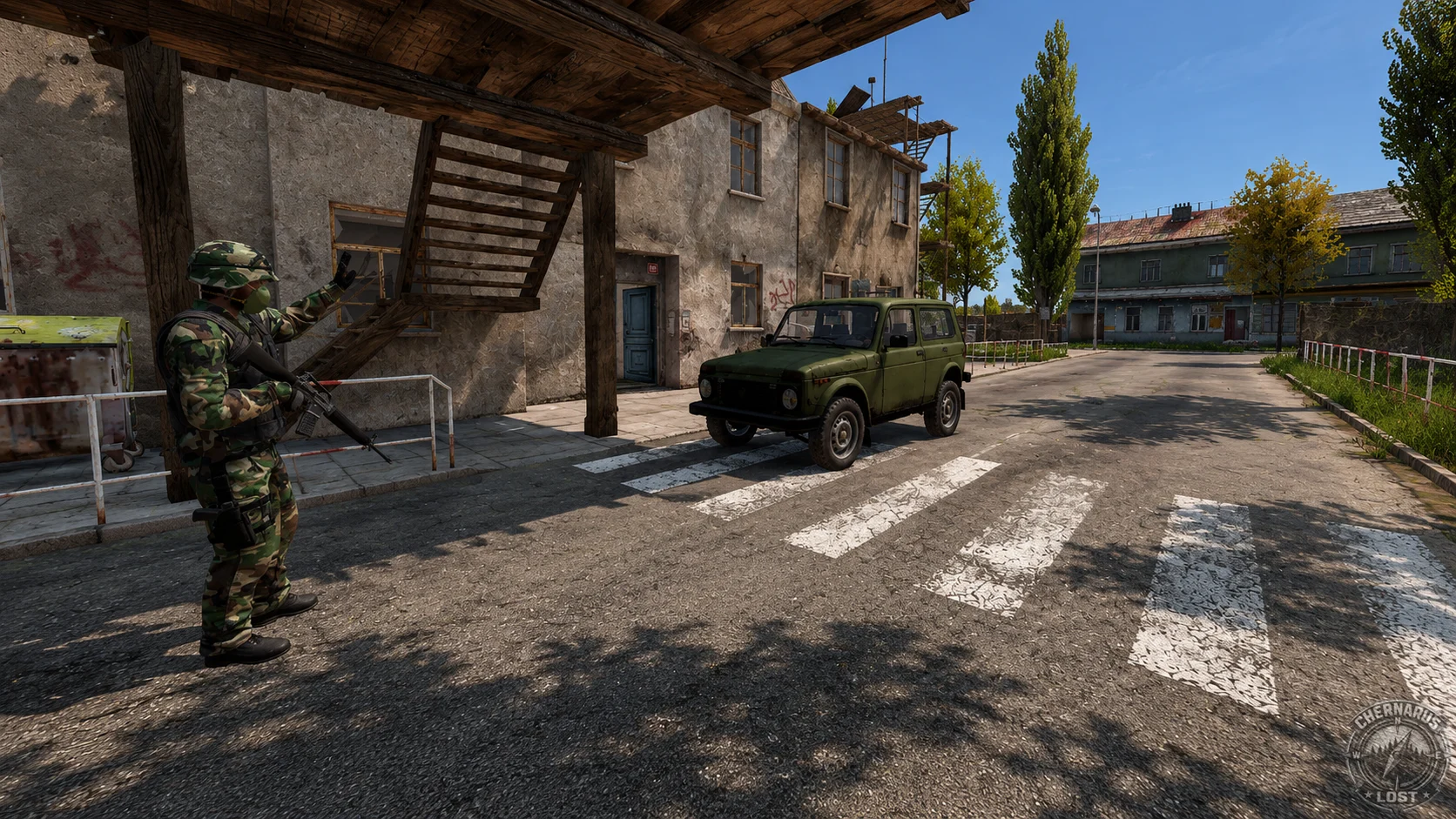 An armed survivor at a checkpoint beside a green vehicle and concrete buildings.