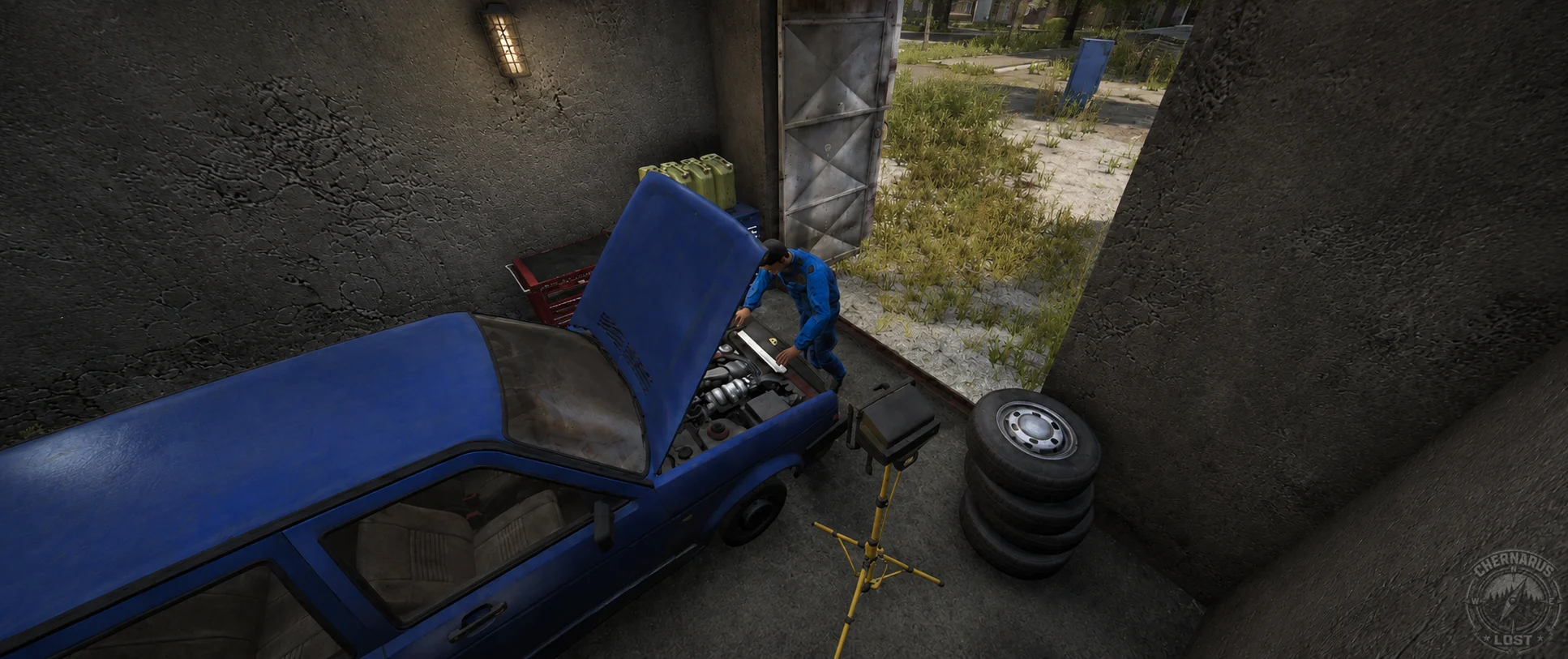 A mechanic working on a blue car with its bonnet open inside a garage.